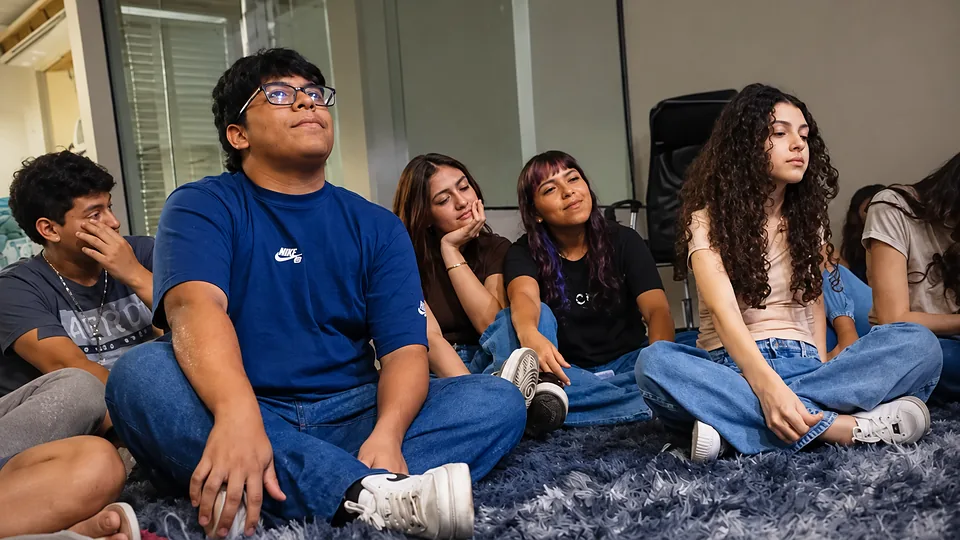 Jovens da Rede UP sentados no tapete, atentos durante um encontro
